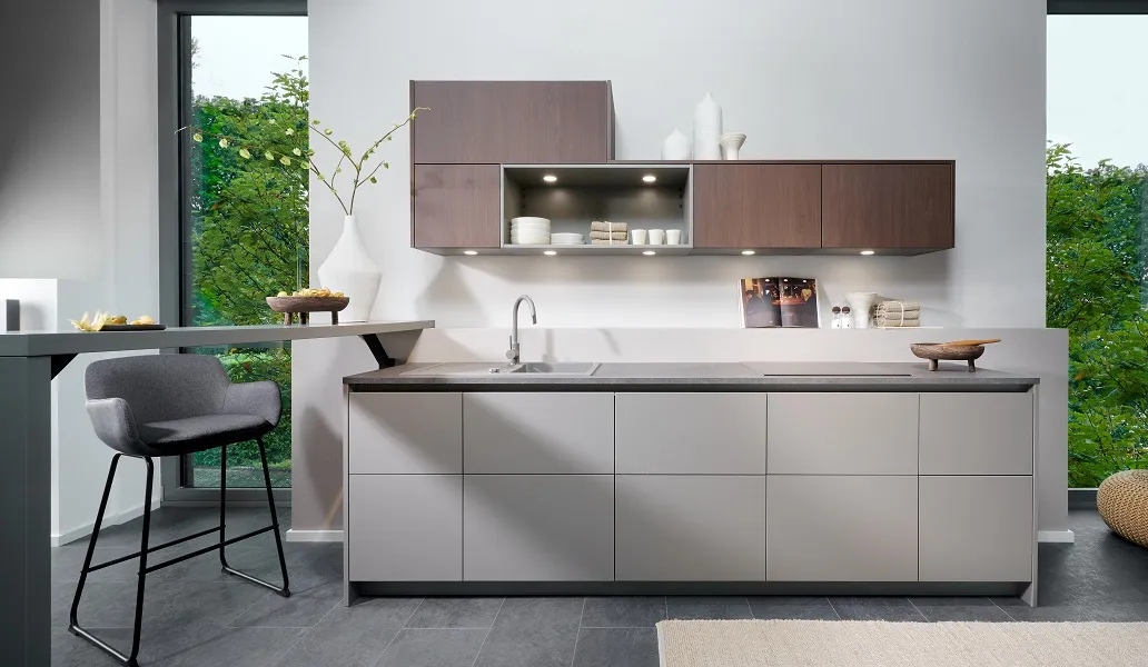 Petite cuisine contemporaine sans poignée coloris beige sable avec rangements hauts asymétriques et bar en retour