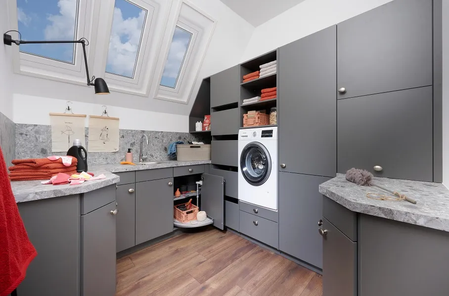 Buanderie sur-mesure avec lave-linge en hauteur, plans de travail et crédences en stratifié granit, casiers coulissants et rangements gris
